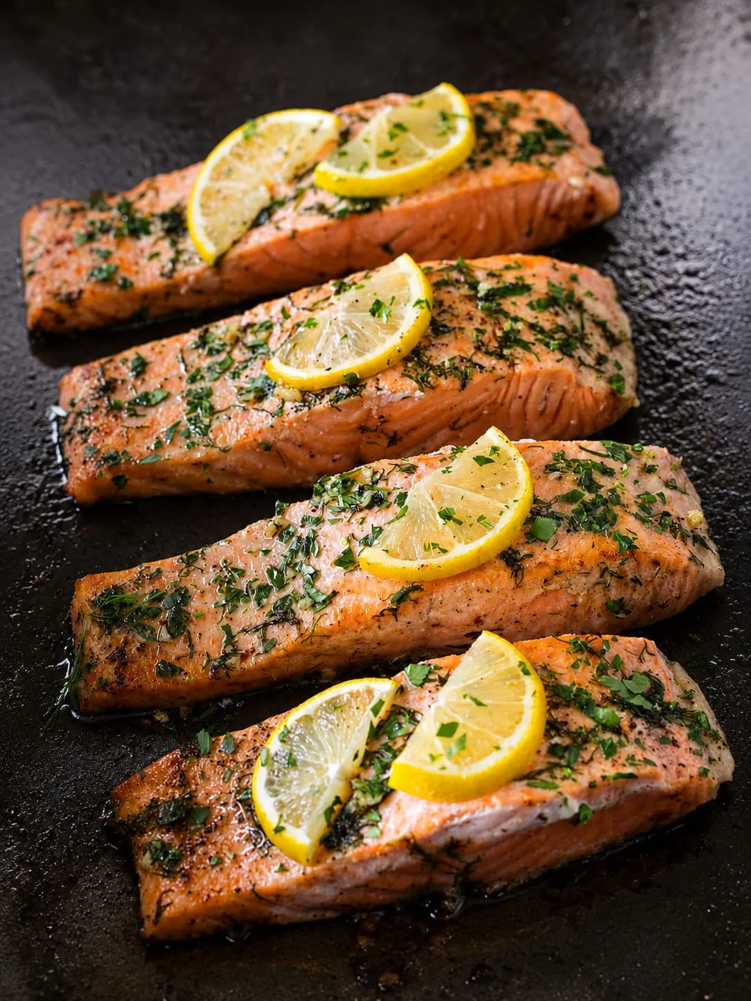 Salmon fillets cooking on a Blackstone griddle with garlic butter sauce