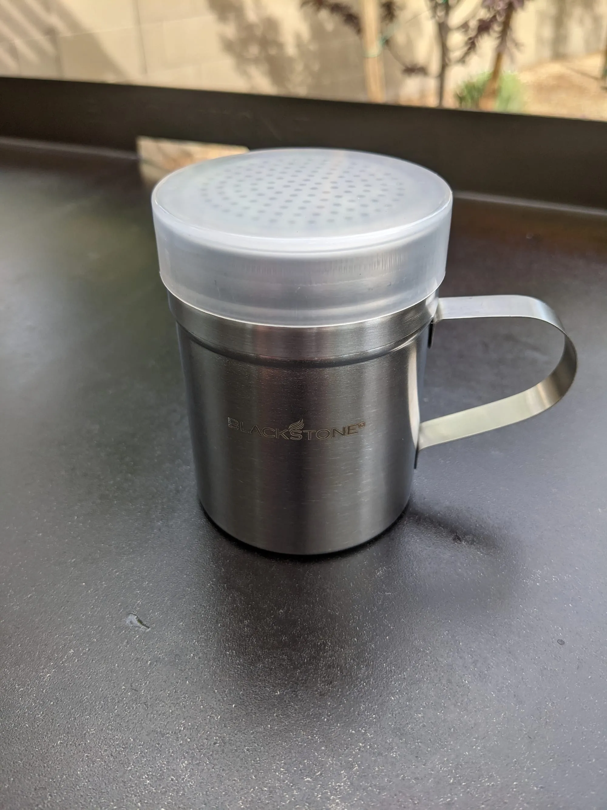 Blackstone griddle seasoning shakers with salt, pepper, and spice blends at the cooking station
