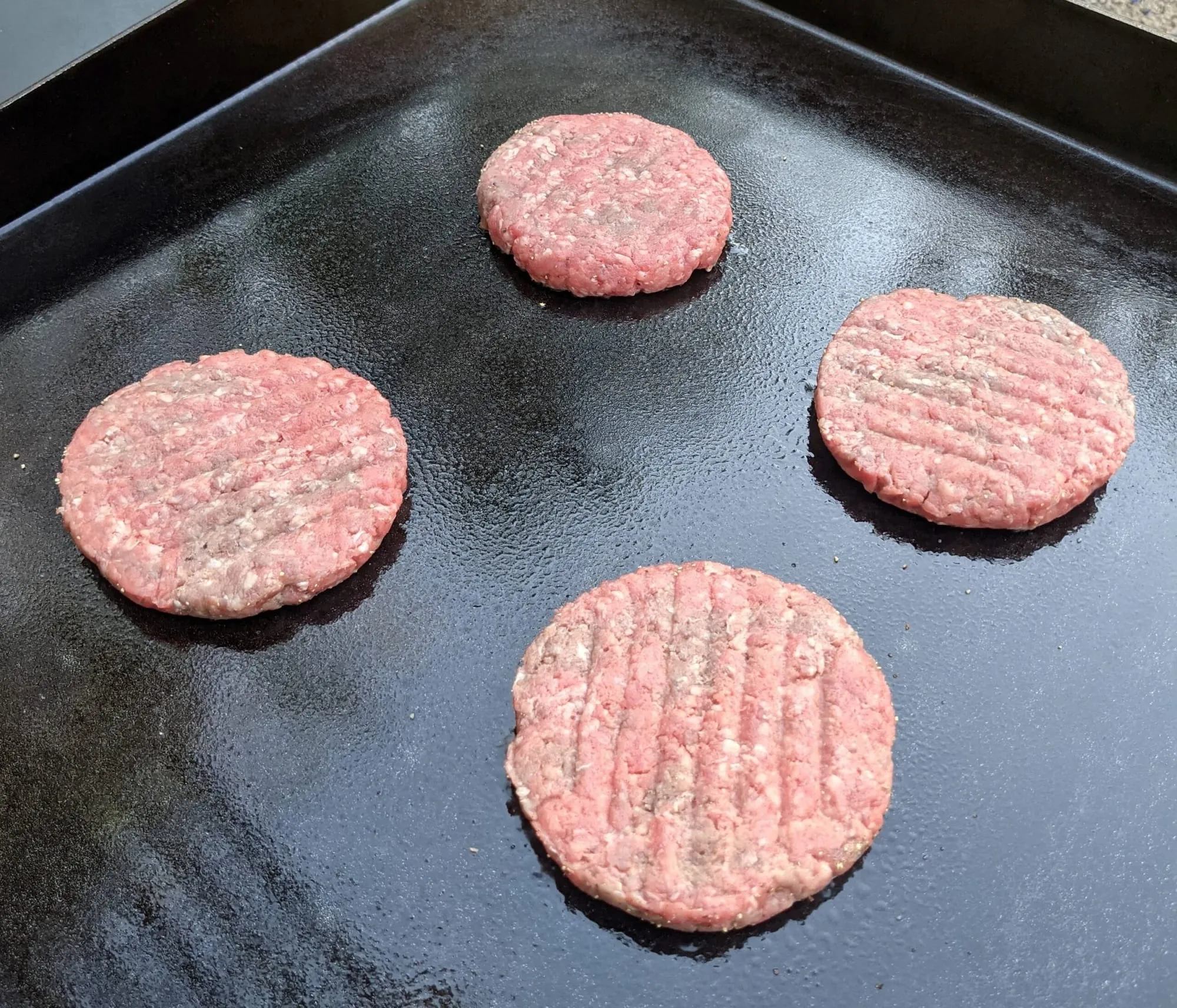 Burger patties cooking on a Blackstone griddle