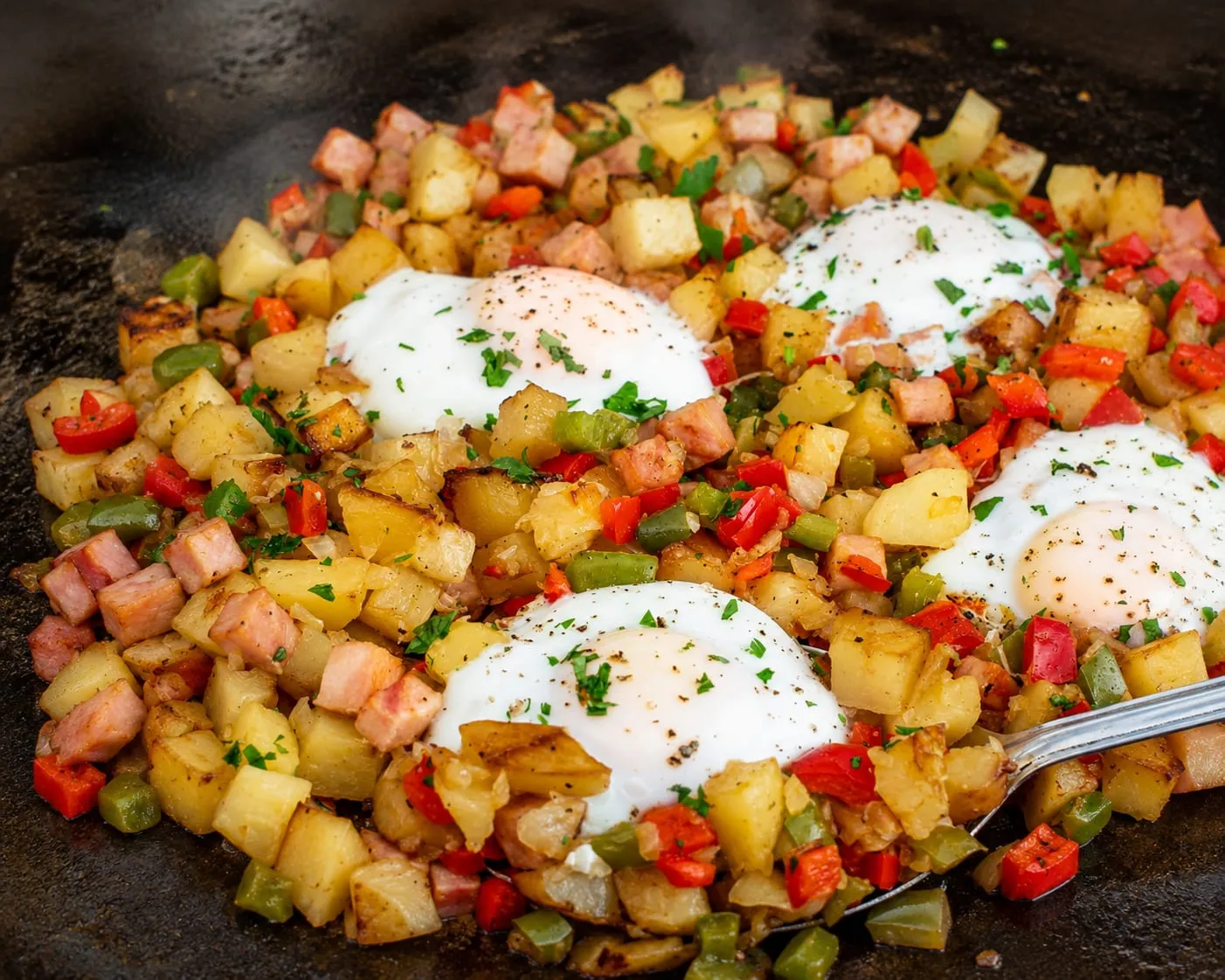 Blackstone breakfast hash with crispy potatoes, peppers, onions, and eggs on a flat-top griddle