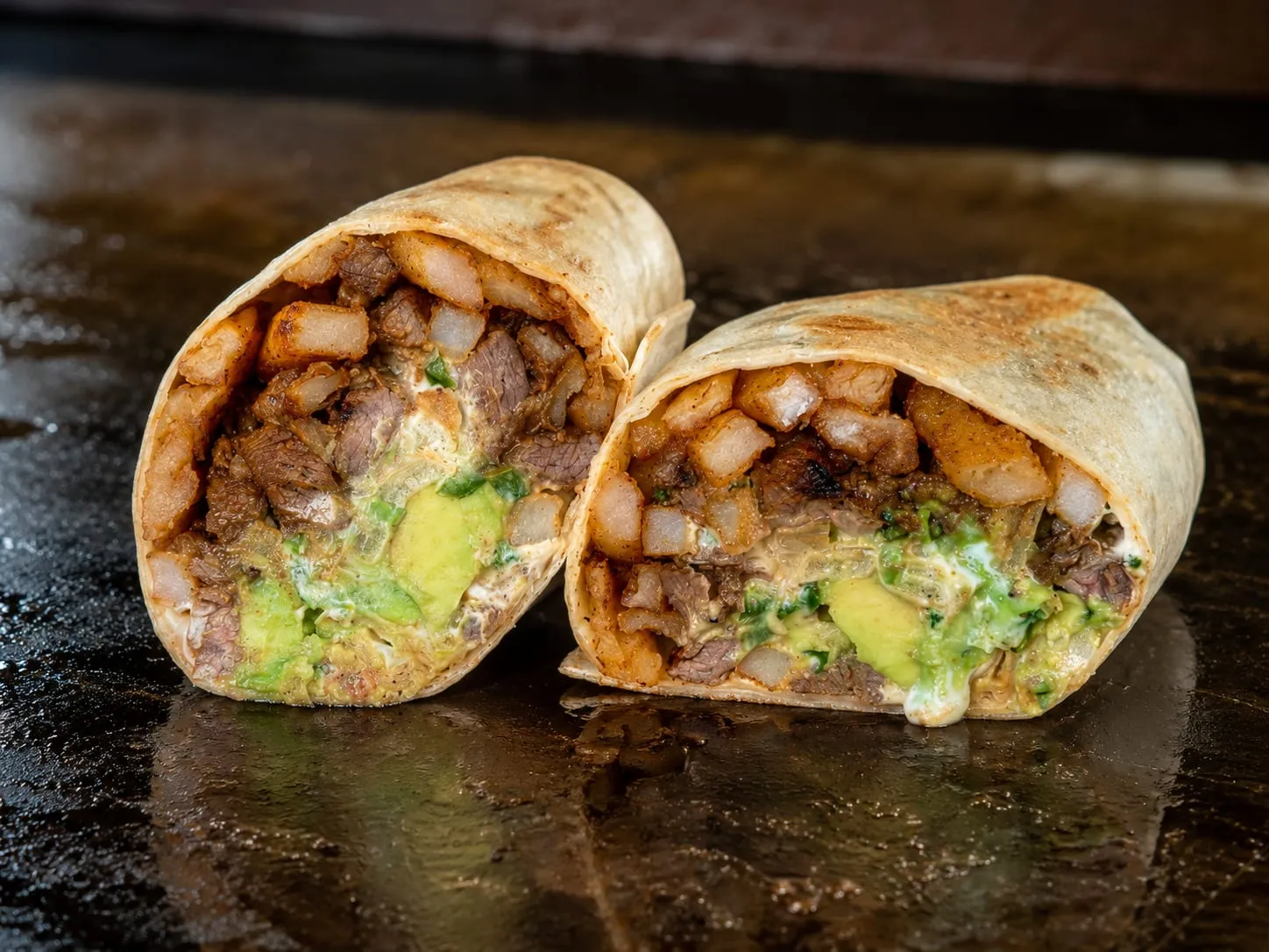 Blackstone California burrito with carne asada, fries, and melted cheese on a grilled flour tortilla