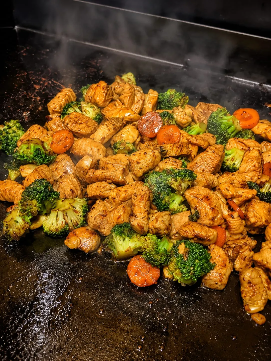 Blackstone chicken stir fry with noodles and vegetables on the flat-top griddle