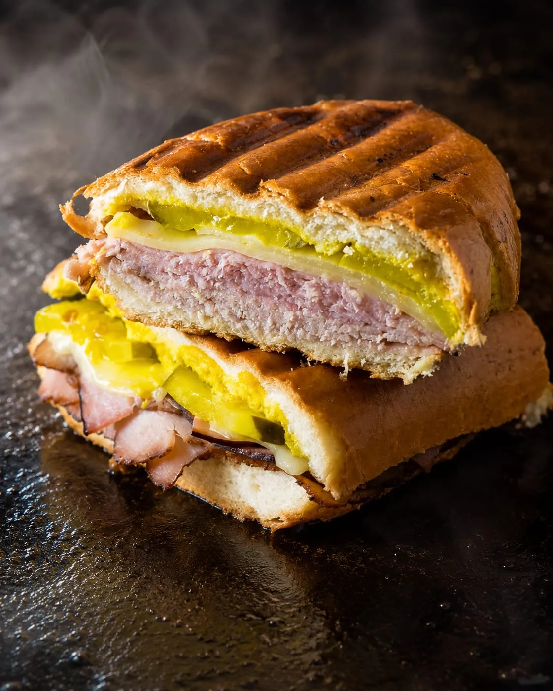 Cuban sandwich pressed flat with golden crust on a Blackstone griddle