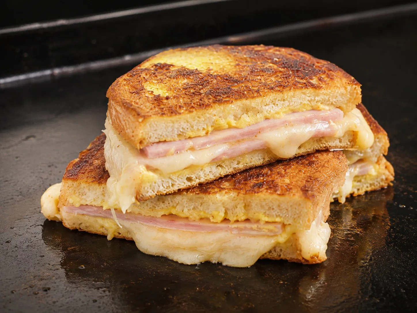 Monte Cristo sandwich cut in half on a Blackstone griddle, golden French-toast crust with ham and melted Swiss