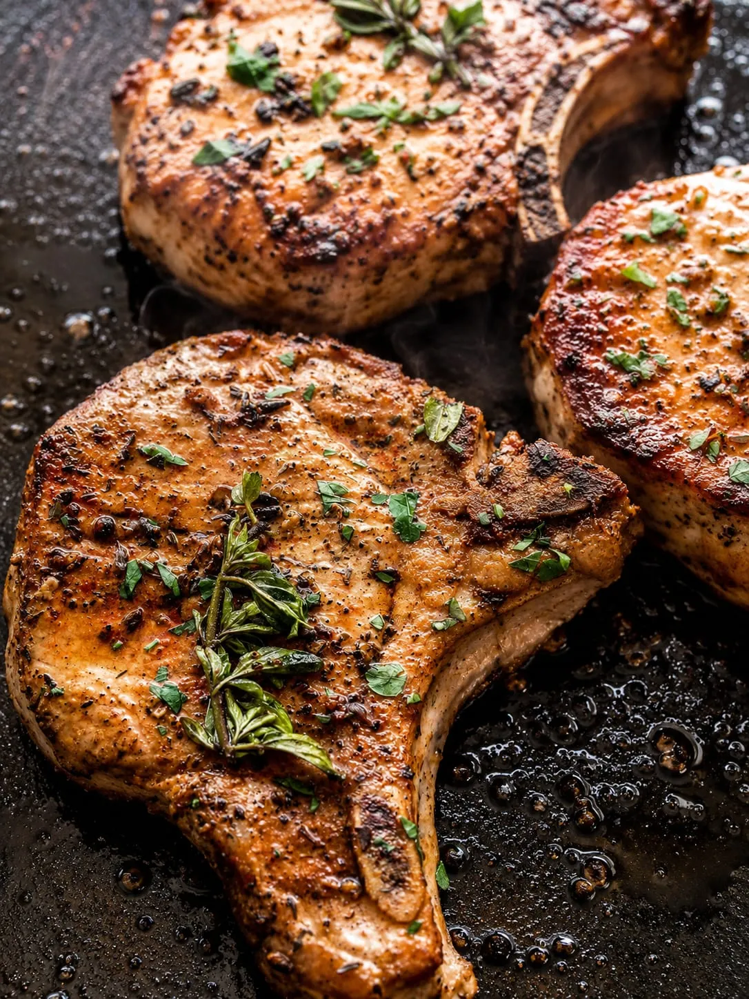 Blackstone pork chops searing on a flat-top griddle with golden crust