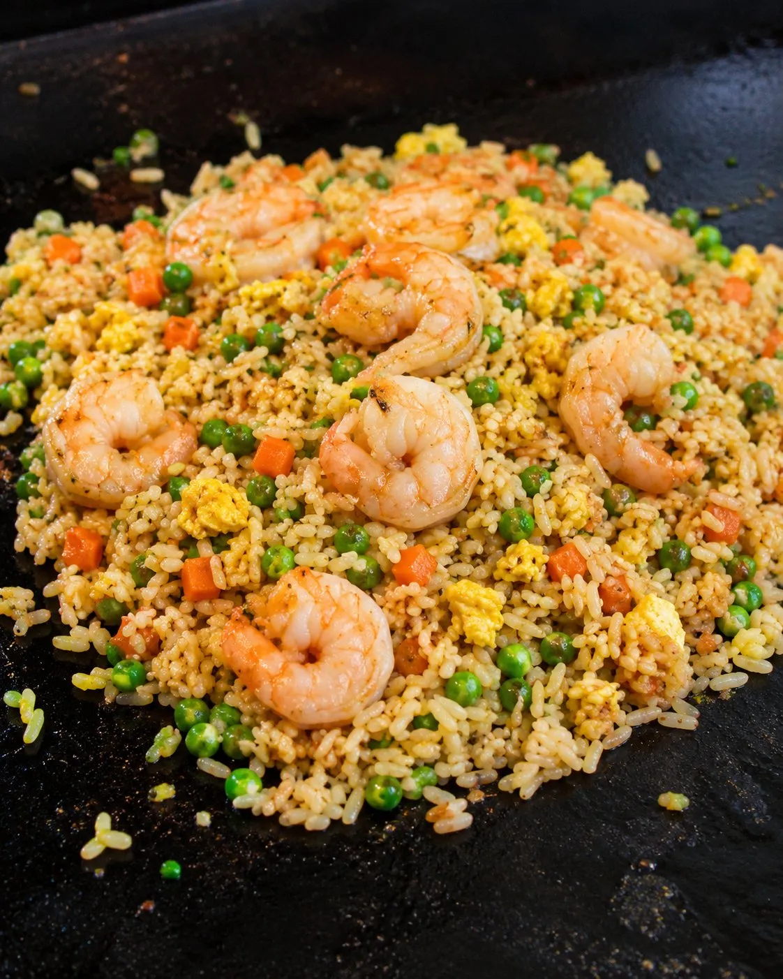 Seared shrimp over fried rice with peas, carrots, and egg on a Blackstone griddle