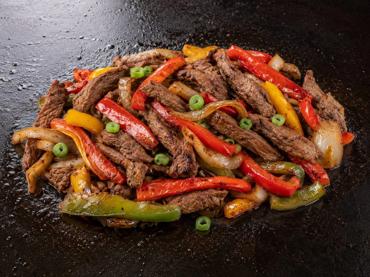 Blackstone steak fajitas with skirt steak, caramelized peppers and onions on a flat-top griddle