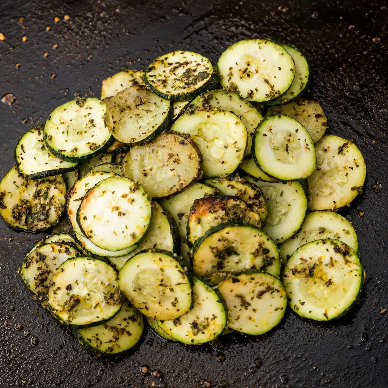Zucchini cooking on a Blackstone griddle with charred edges